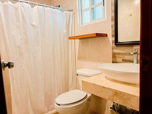 Ein Badezimmer mit Duschvorhang, Toilette, Waschbecken und einem Spiegel über dem Waschbecken.