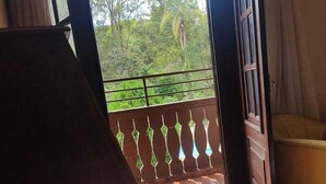 A room with a large window, a wooden door, and a view of trees outside. - Hotel Floresta (Poços de Caldas)
