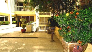 A paved outdoor area with potted plants and a building in the background. - Apartamento Arena - Smr236a (Santa Marta)