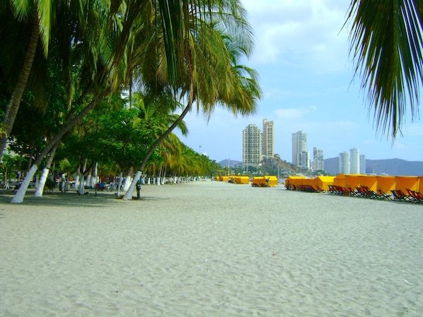 Ein Strand mit Palmen und gelben Strandsonnenschirmen.