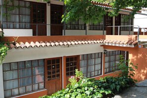 A building with multiple windows and doors, some with numbers. There are plants growing around the building. - Hotel La Ballena (Punta del Este)