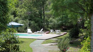 A backyard with a swimming pool, lounge chairs, and a covered area. - Hotel La Ballena (Punta del Este)