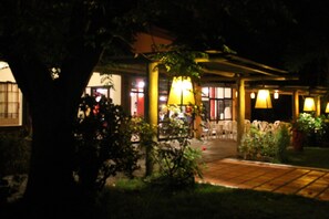 An outdoor area with a covered seating area, tables, and chairs. There are potted plants and a lamp post. - Hotel La Ballena (Punta del Este)