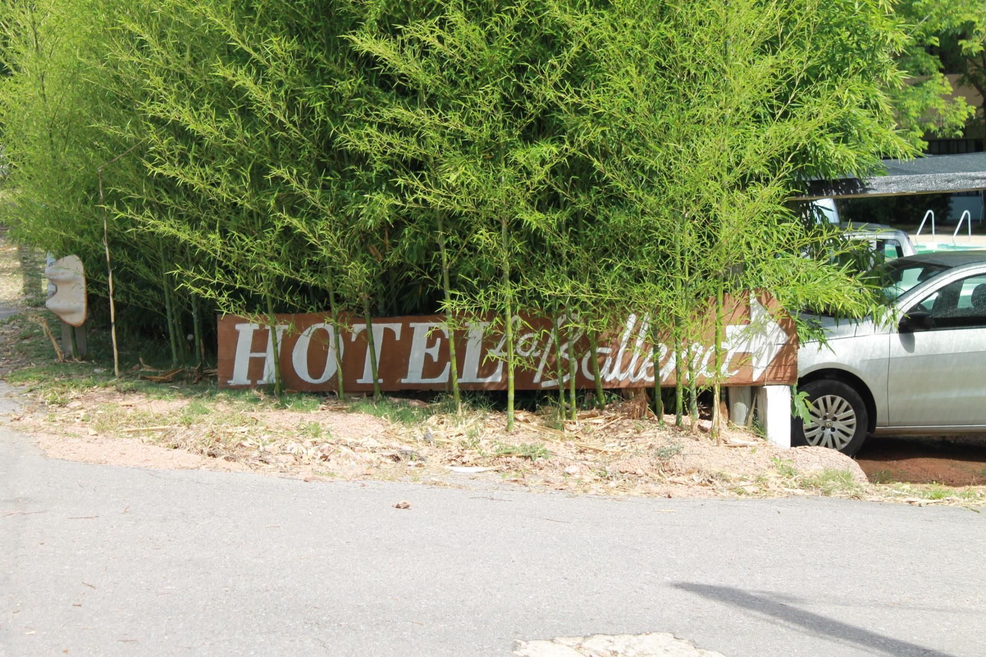 A sign for a hotel with the name partially obscured by foliage.