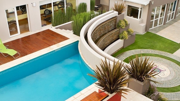Une maison moderne dotée d’une piscine, d’un patio et d’un jardin aménagé en cercle.