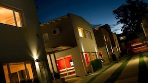 Un immeuble résidentiel moderne comprenant plusieurs logements, chacun doté de grandes fenêtres et d’une entrée bien éclairée.