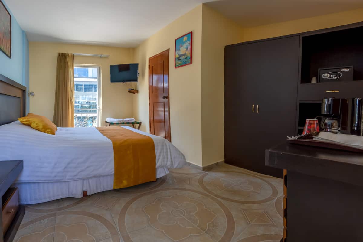 A hotel room with a bed, a desk, a TV, a wardrobe, and a window with curtains.