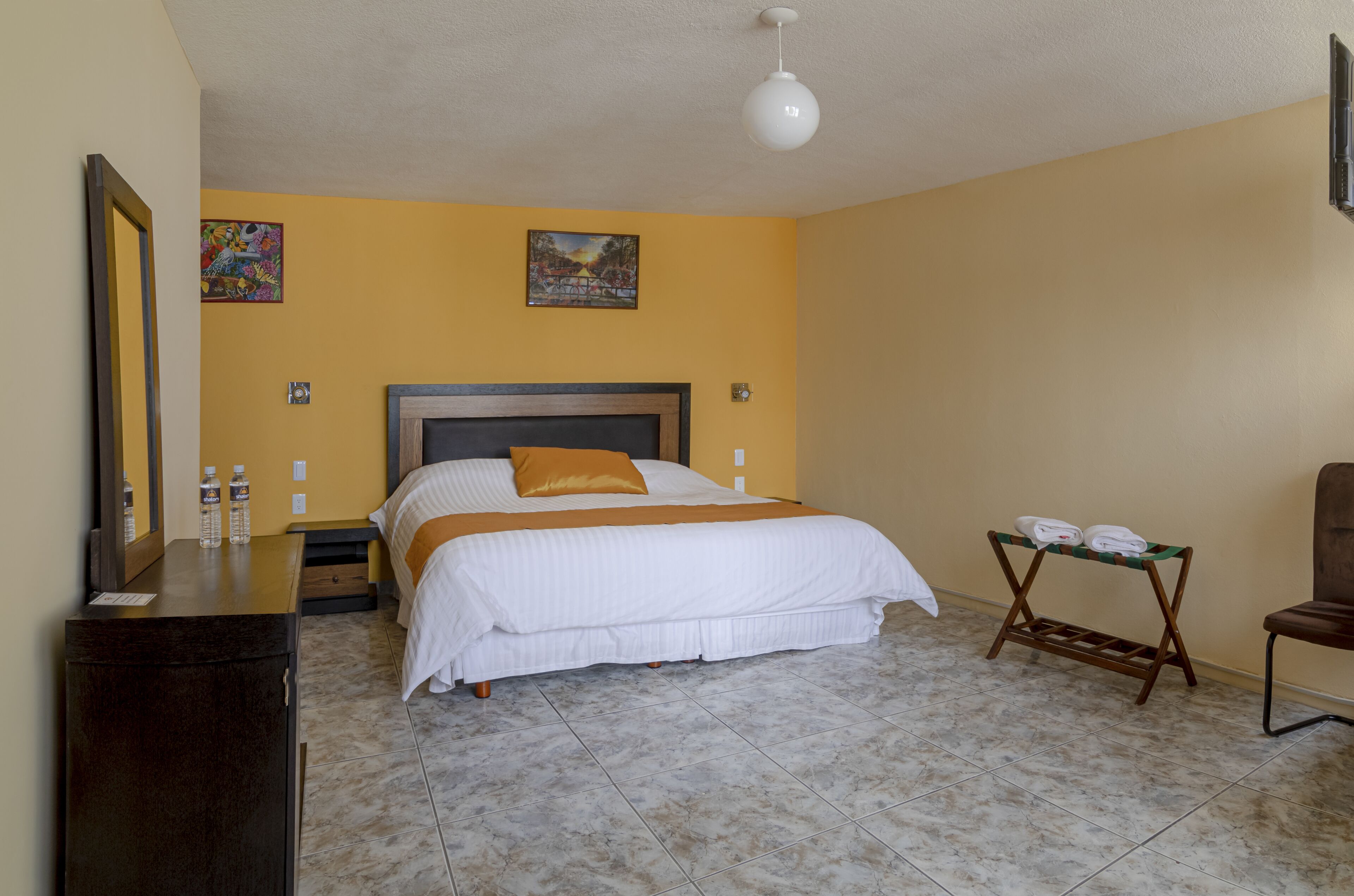 Un dormitorio con una cama, una mesita de noche, un aparador, una silla y una pequeña mesa con toallas.