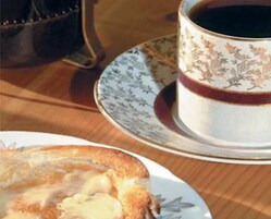 Una mesa con un plato de comida y una taza de café.