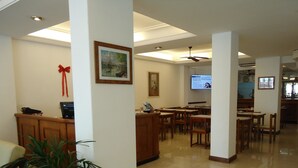A hotel lobby with a reception desk, seating area, and a television screen. - Hotel Playa Suites CR (Mar Del Plata)