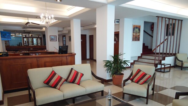A spacious lobby with a checkered floor, a sofa set with striped cushions, a coffee table, and a potted plant. - Hotel Playa Suites CR (Mar Del Plata)