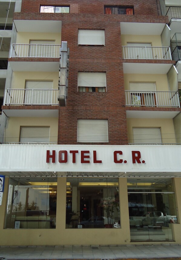 A hotel with a sign reading "HOTEL C.R." and multiple balconies.