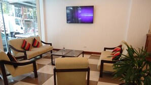 A hotel lobby with a checkered floor, two sofas with striped cushions, a coffee table, and a potted plant. - Hotel Playa Suites CR (Mar Del Plata)