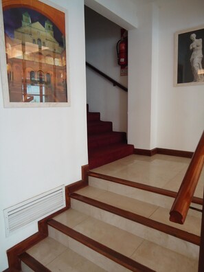 Staircase features a framed picture of a historic building and a classical sculpture.