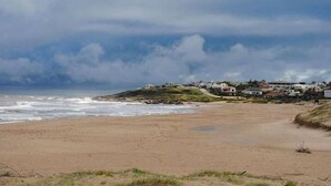 Ein Strand mit sandigem Ufer und einer Reihe von Häusern im Hintergrund.