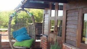 Eine Holzterrasse mit einem Hängesessel und einem gestreiften Liegestuhl.