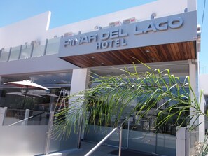 Exterior do Hotel Pinar Del Lago, com design moderno, apresentando uma placa em destaque e entrada em vidro.