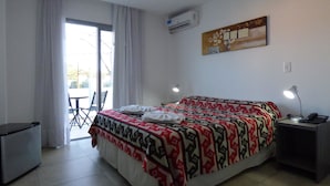 A hotel room with a bed, a desk, a chair, an air conditioner, and a window with curtains. - Pinar del Lago (Villa Carlos Paz)