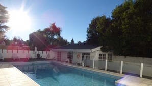 A swimming pool with a tiled deck, a covered seating area, and a lifeguard stand. - Pinar del Lago (Villa Carlos Paz)