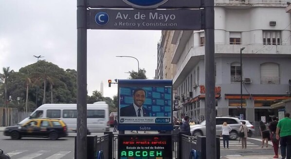 A street scene with a digital display board at an intersection, displaying a message in Spanish. - Du Helder (Buenos Aires)
