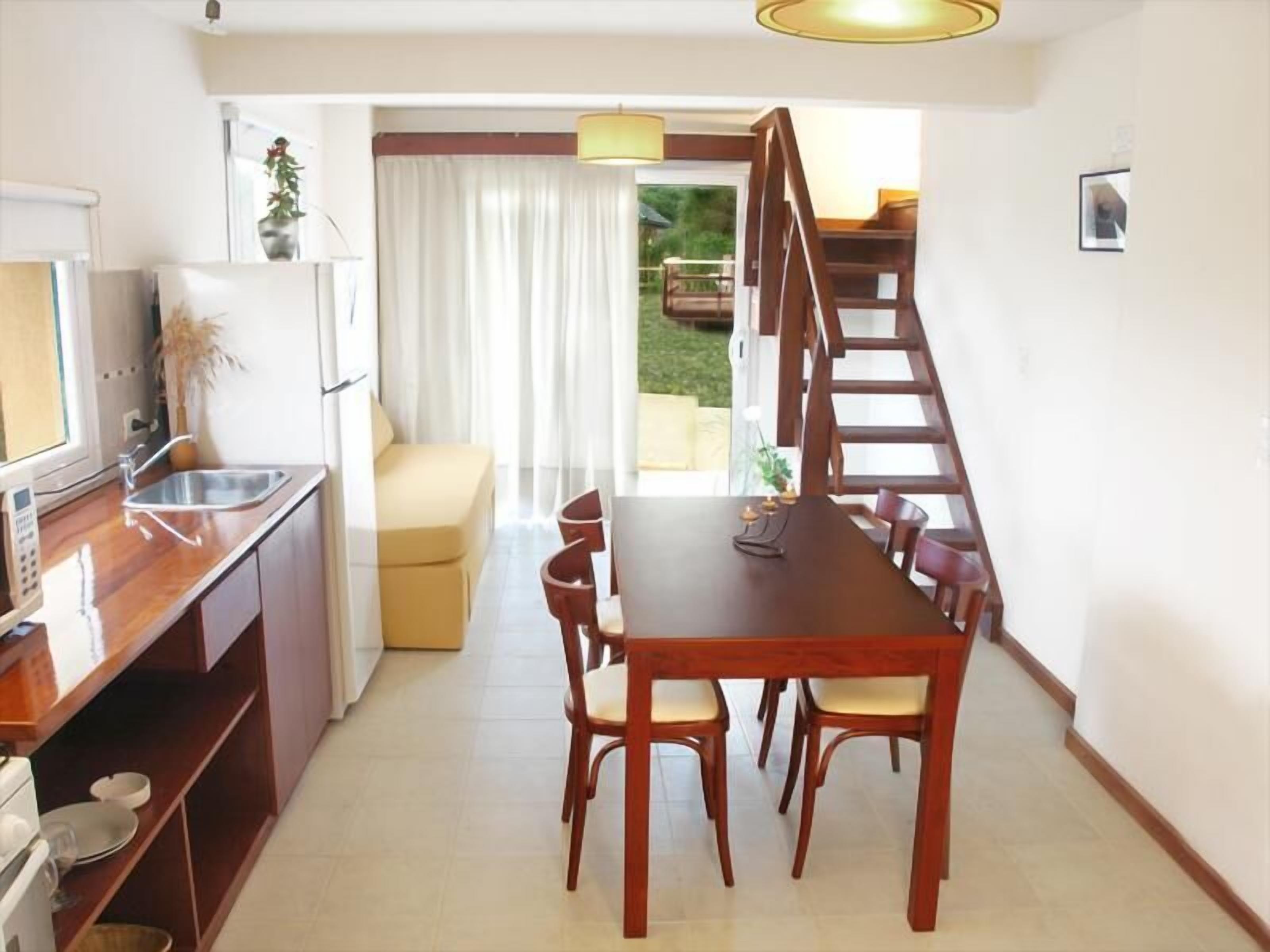 A compact kitchen with a dining area, a staircase, and a view of the outdoors.