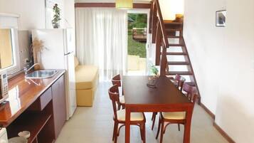 A compact kitchen with a dining area, a staircase, and a view of the outdoors.