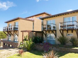 A multi-story building with balconies, a stone retaining wall, and various plants.