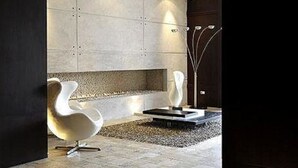A modern interior with a stone wall, two white chairs, and a decorative floor lamp. - Ritz Plaza Suite (Quito)