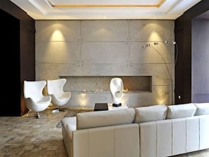 A modern living room with a fireplace, two white armchairs, and a beige sofa. - Ritz Plaza Suite (Quito)