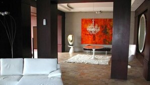A modern lobby with a white sofa, a round table, and a large abstract painting on the wall. - Ritz Plaza Suite (Quito)