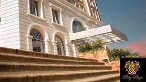 A multi-story building with a curved facade, large windows, and a prominent entrance with steps. - Ritz Plaza Suite (Quito)