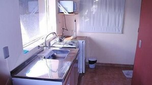 A compact kitchen with a sink, a microwave, and a small window. - Monoambiente del Trebol (San Carlos de Bariloche)