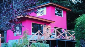 A pink building with a wooden deck and a bridge. - Monoambiente del Trebol (San Carlos de Bariloche)