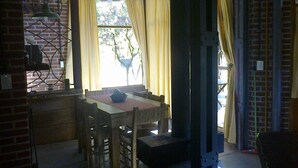 A dining area with a brick wall, a wooden table, and yellow curtains. - Alma del Monte (Mar de las Pampas)