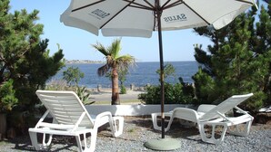 A beachside seating area with white lounge chairs and a large umbrella. - Hotel Morgan Bay (Piriapolis)