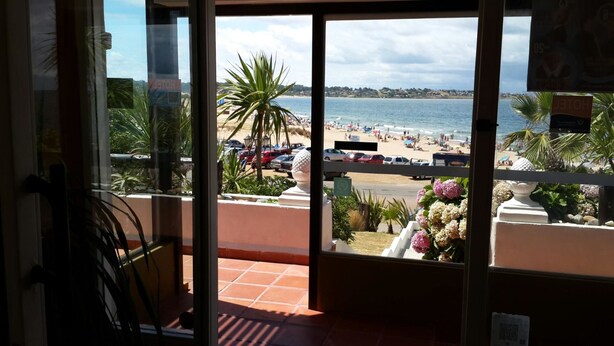 A hotel room with a view of a beach, a balcony with potted plants, and a sign indicating the hotel name. - Hotel Morgan Bay (Piriapolis)