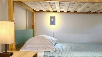 Una cama litera con escritorio y lámpara, un enchufe de pared y baldosas de suelo estampadas.