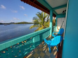 Un balcón con vista al mar, una palmera y una silla azul.