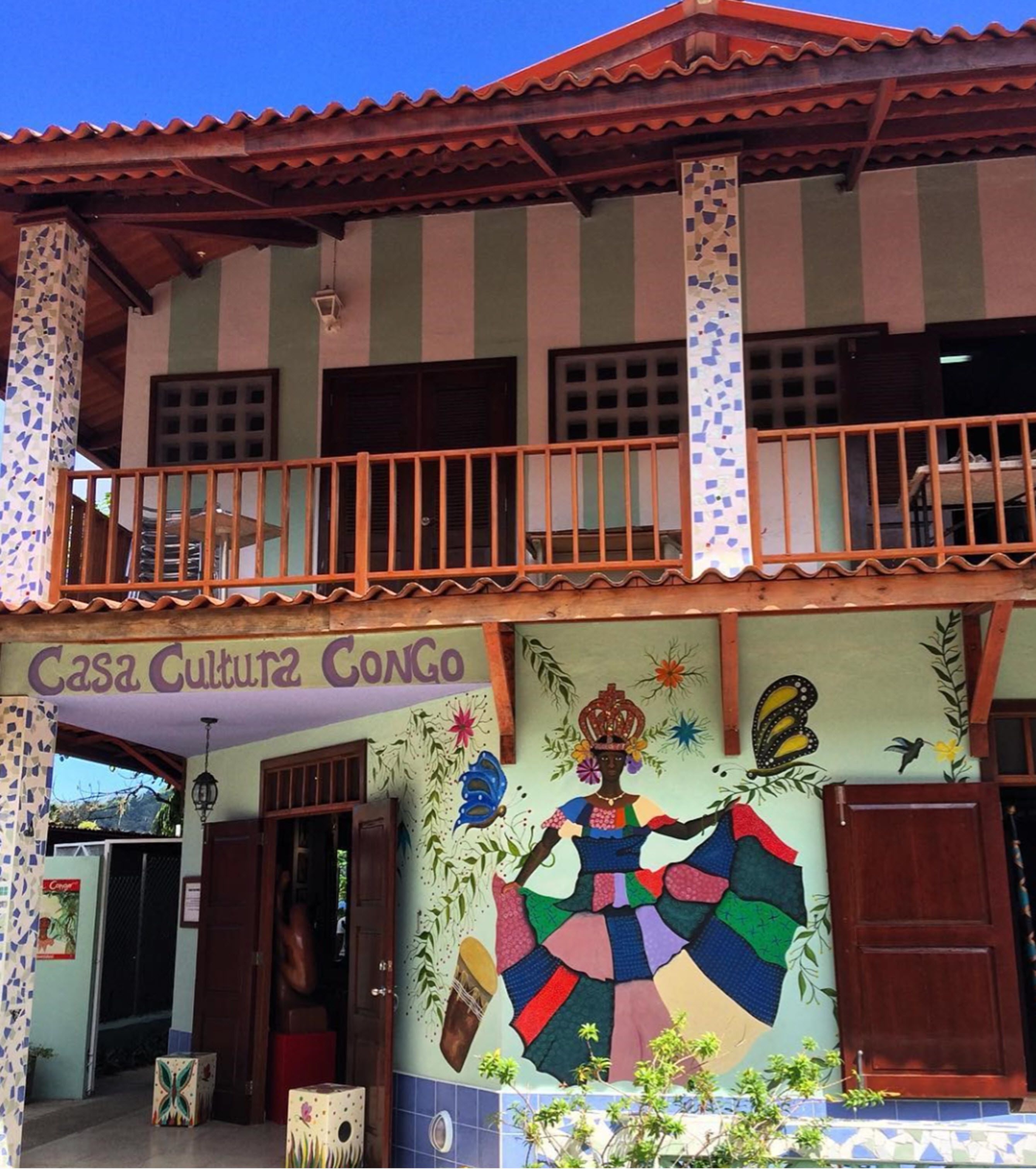 A two-story building with a balcony and a mural depicting a figure in traditional attire.