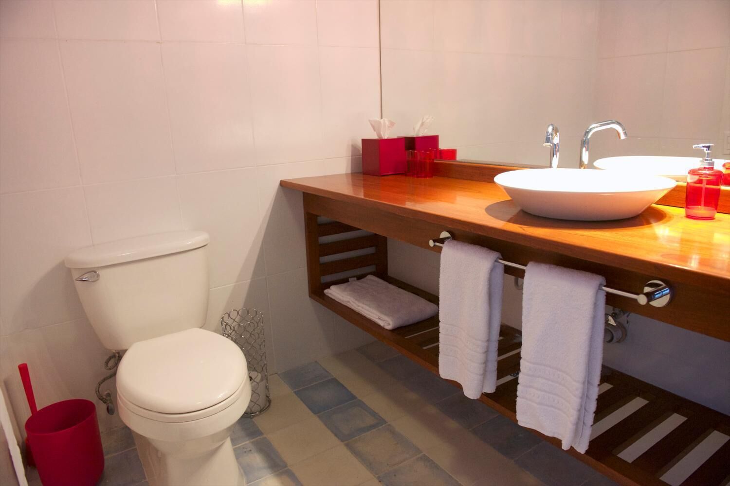Un baño con inodoro, lavamanos y tocador de madera.