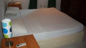 Ein Hotelzimmer mit Bett, Nachttisch mit Lampe und kleiner Anrichte.