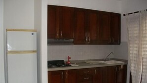 Eine Küche mit Holzausstattung, einem weißen Kühlschrank, einer Spüle und einem Fenster mit Vorhang.