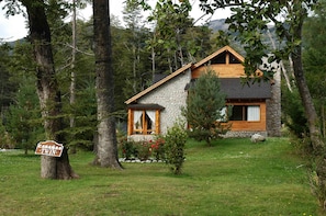 A cabin with a stone exterior and wooden accents, surrounded by trees and a sign indicating 'Cabanas Twin'.