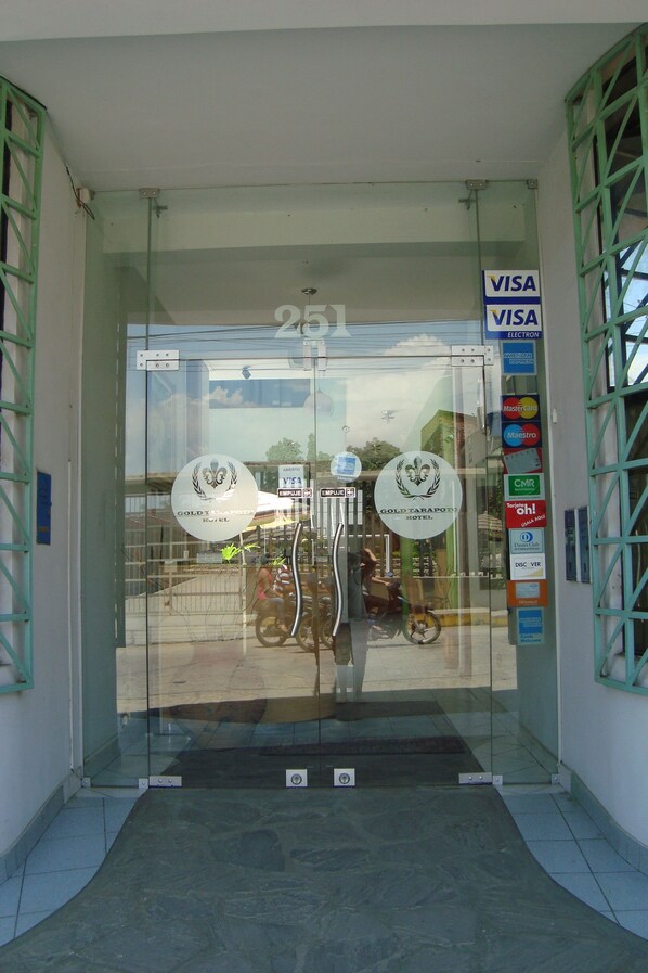 A hotel entrance with glass doors, Visa and Mastercard logos, and a sign for the Gold Tarapoto Hotel.