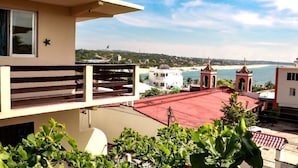 A view from a balcony overlooking a beach with a church and residential buildings. - Rivera del Mar (Puerto Escondido)