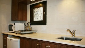 Een keuken met houten kastjes, een wit aanrecht, een magnetron, een waterkoker en een spoelbak.