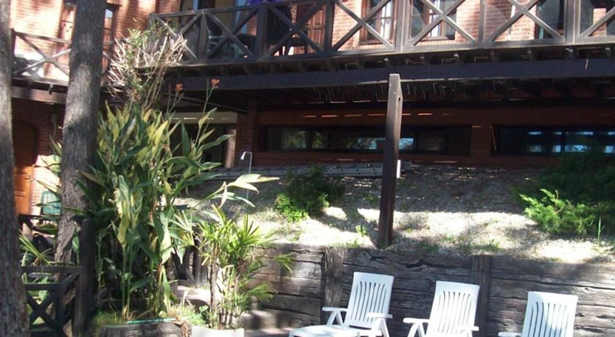 A patio area with white chairs, a wooden deck, and a stone wall.