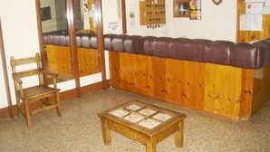 Una habitación con un banco de madera, una mesita y un espejo en la pared.