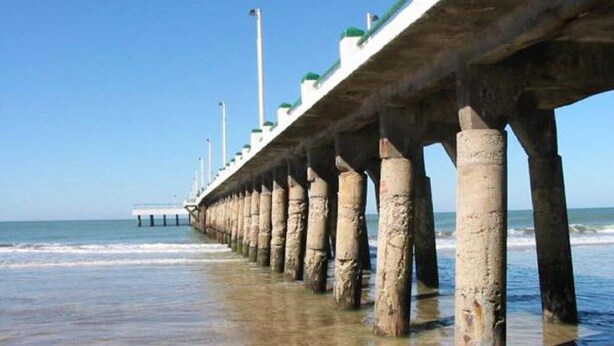 Un muelle que se adentra en el océano bajo un cielo despejado.