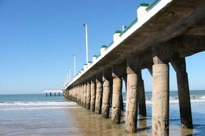 A pier extending into the ocean with a clear sky above.